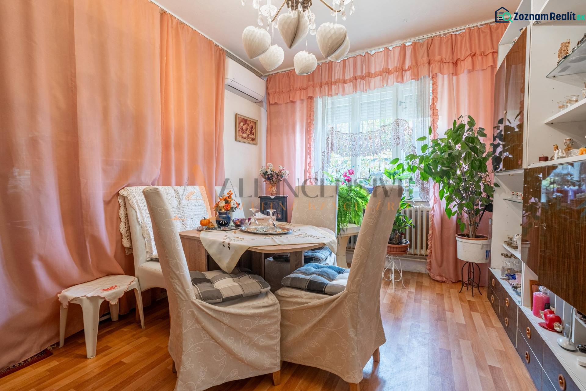 Jídelna v rodinném domě, závity na stěně, pokojové rostliny, podlaha s dřevěným dekorem.