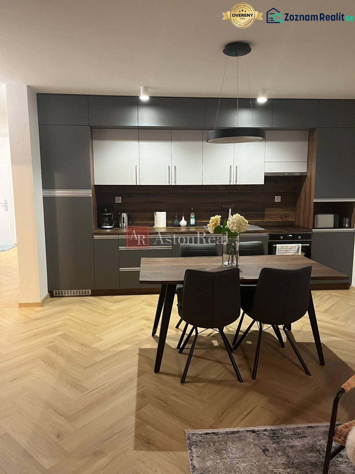 Kuchyně ve 3-pokojovém bytě se šedými skříňkami a podlahou s dřevěným dekorem.