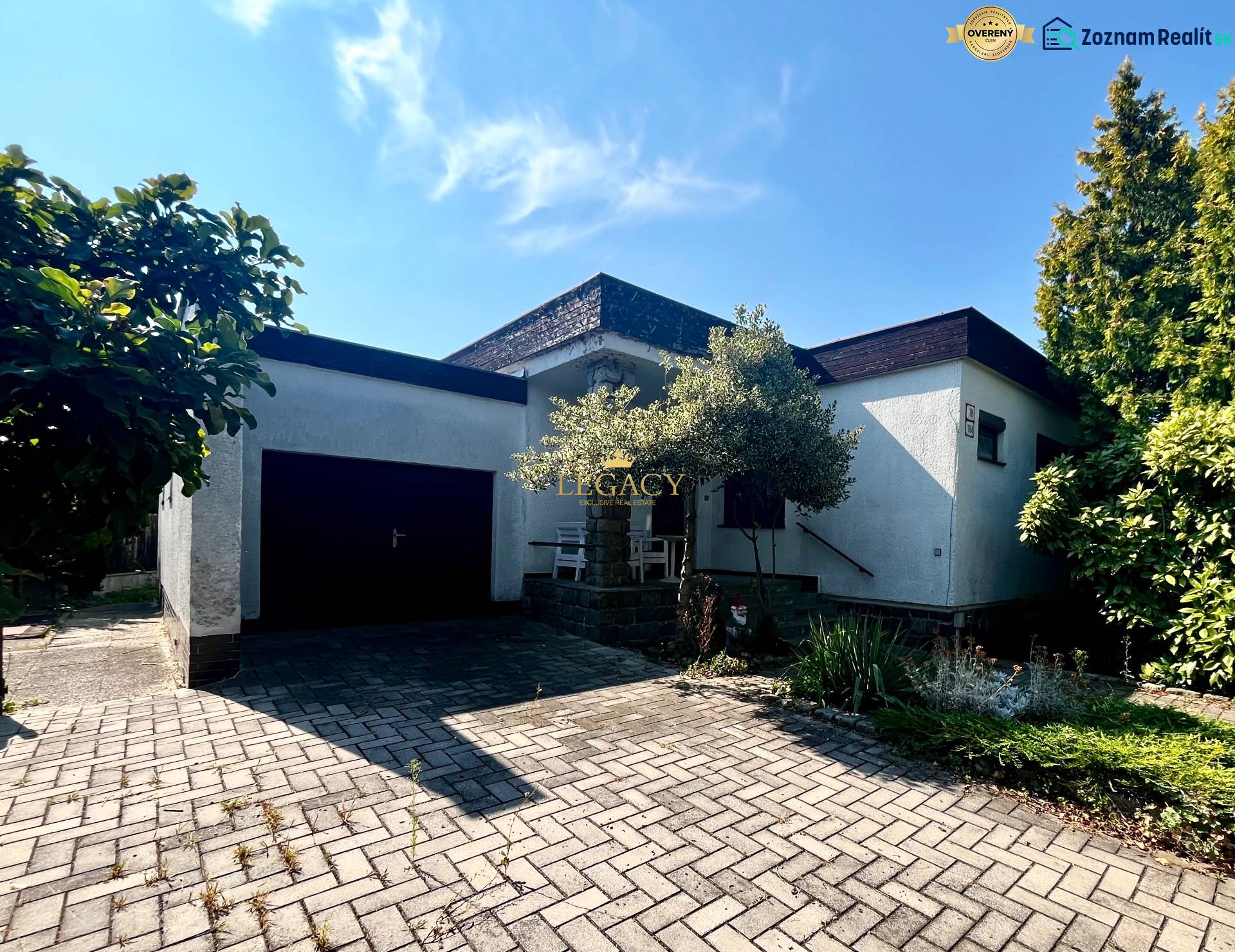 Rodinný dům v Ivance pri Dunaji s garáží a květinovým záhonem, na dlážděném chodníku.