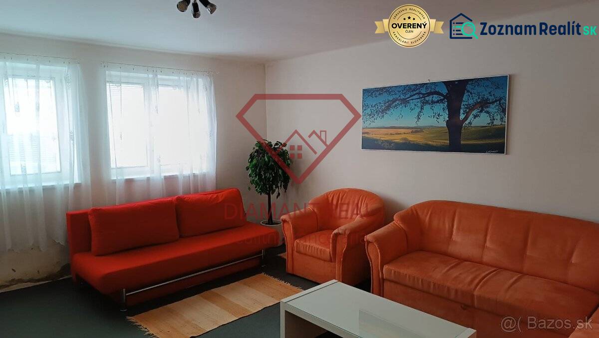 Obývací pokoj v rodinném domě s oranžovou sedačkou, křesly a obrazem krajiny.