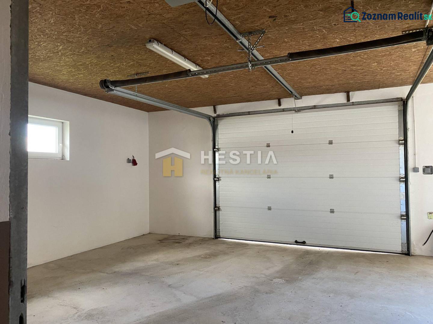 Interiér skladů a hal s garážovými vraty a betonovou podlahou.