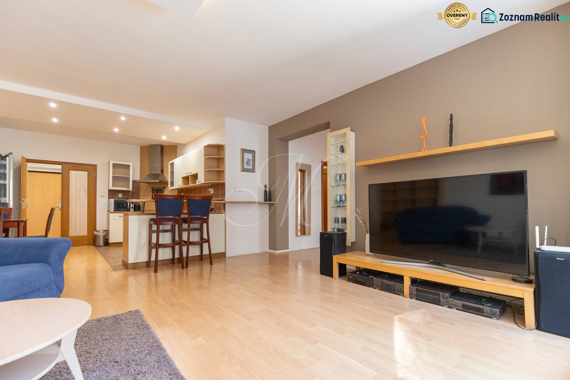 Obývací pokoj v 3-pokojovém bytě se zařízením a podlahou s dřevěným dekorem.