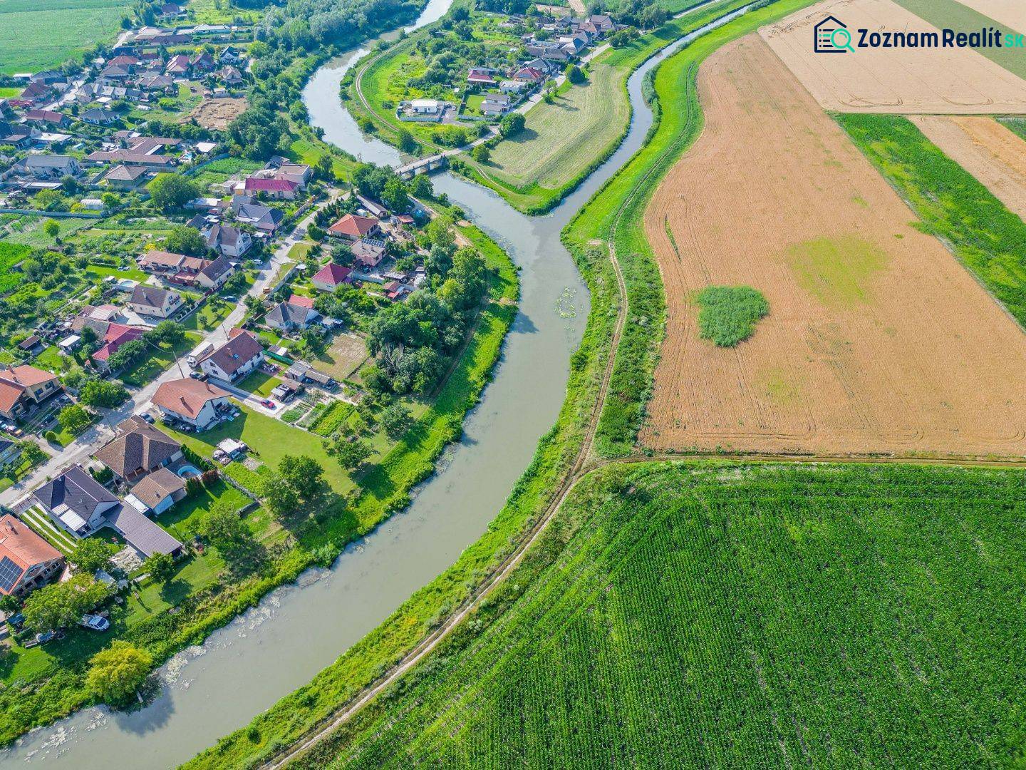 Řeka tekoucí podél zemědělských a lesních pozemků v Černé Vodě, vedle obce.