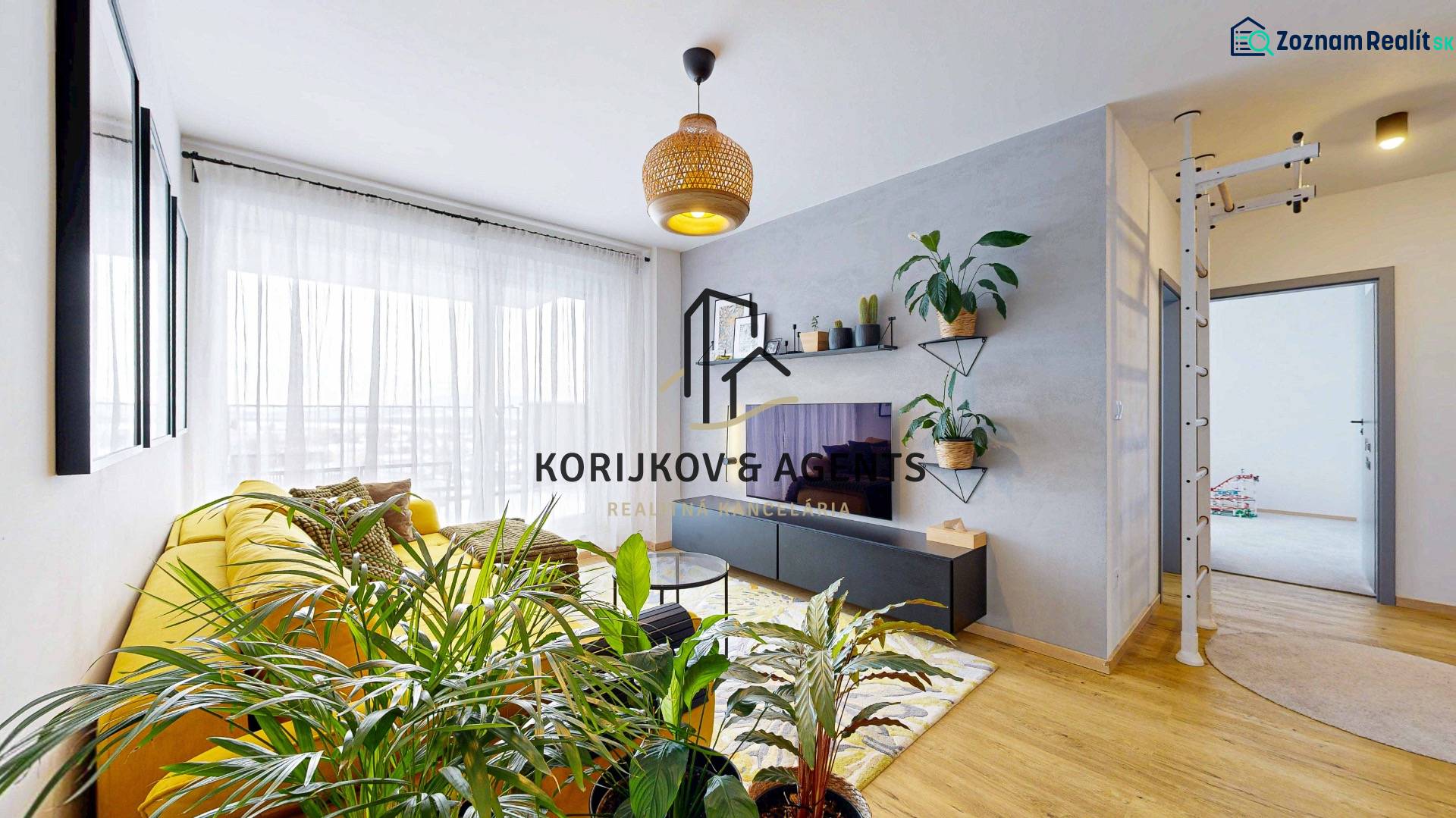 Obývací pokoj v 3pokojovém bytě s velkou žlutou sedačkou a rostlinami, podlaha s dřevěným dekorem.