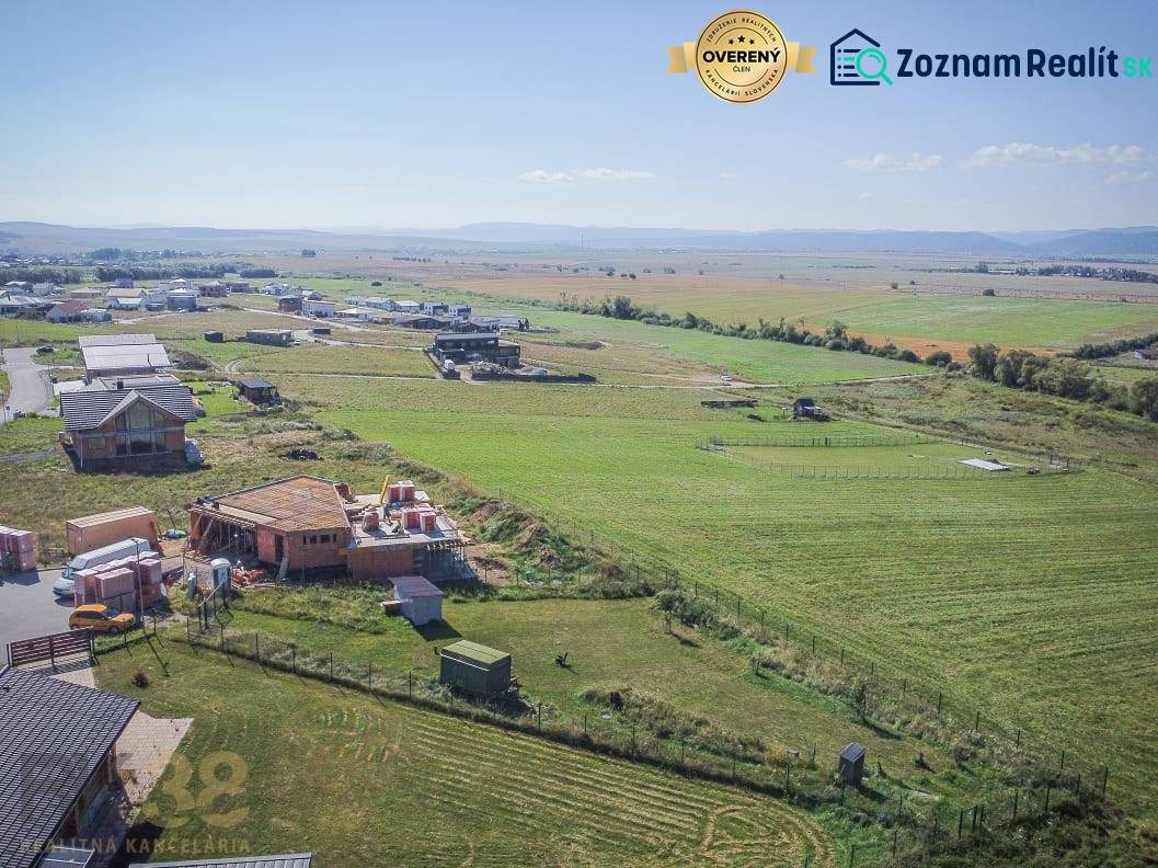 Pozemky - bydlení v Mlynici; rozestavěné domy a rozsáhlá pole pod slunečnou oblohou.