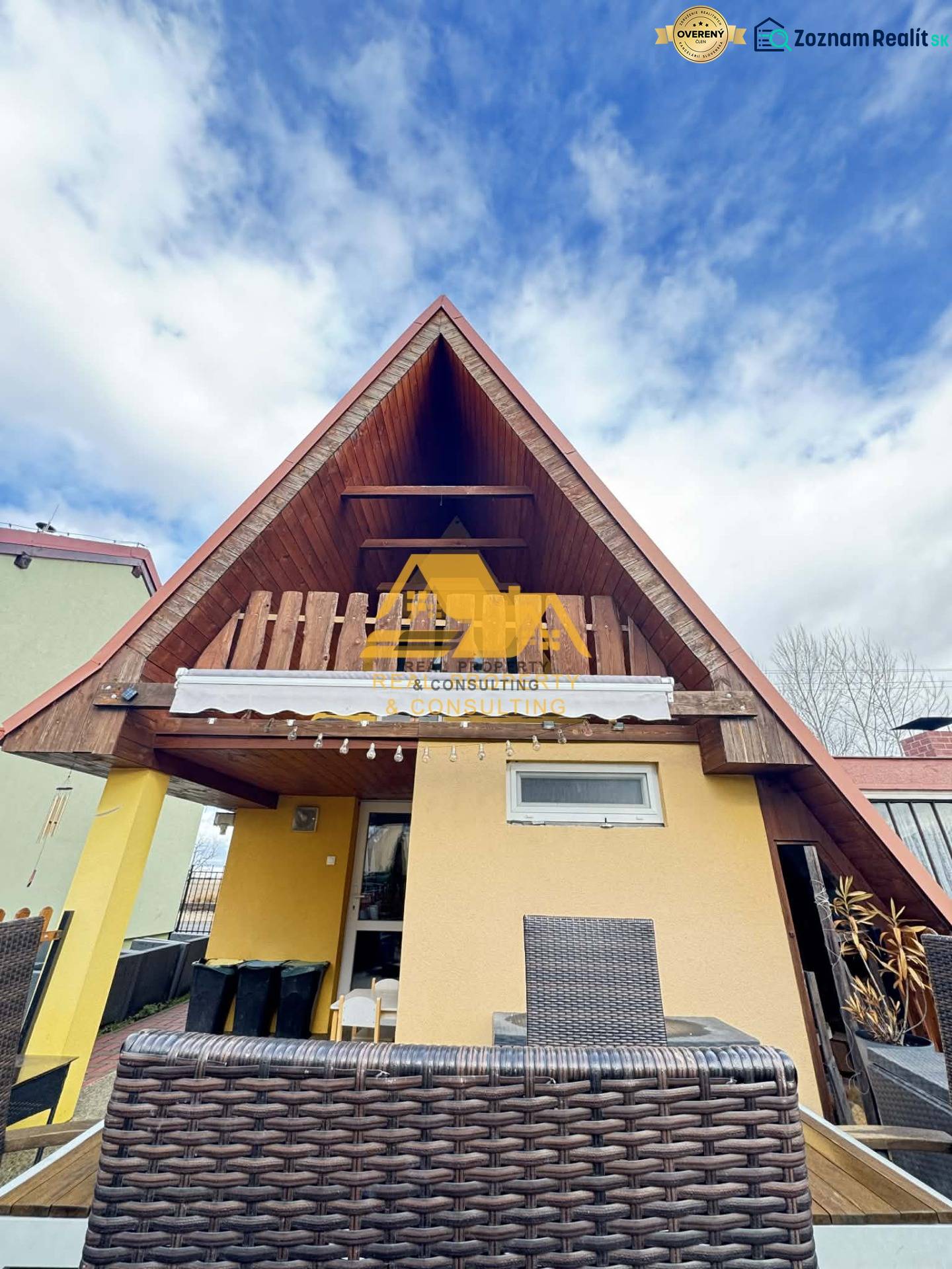 Dřevěná chata s terasou v Nových Zámcích pod modrou oblohou.