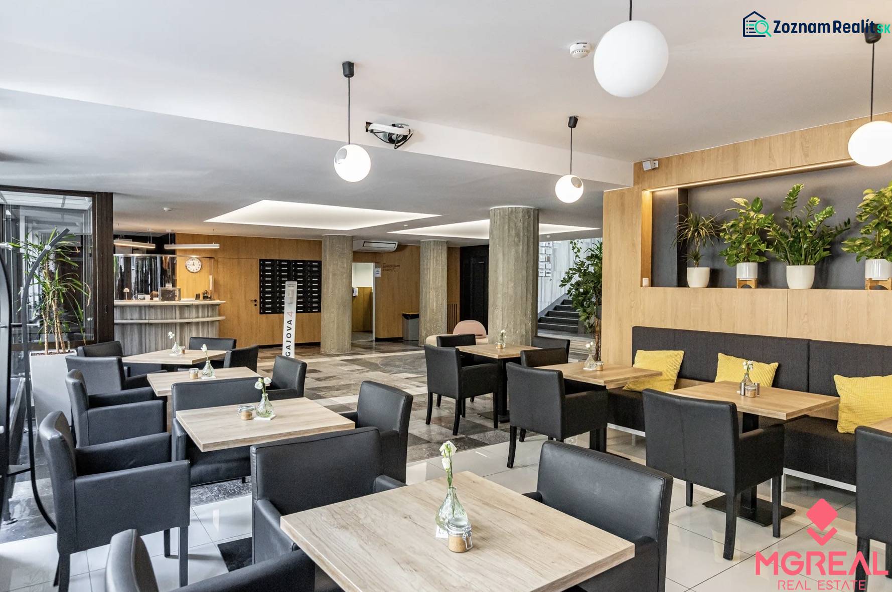 Kanceláře s podlahou s dřevěným dekorem, stoly, černými židlemi a rostlinami v Bratislavě.