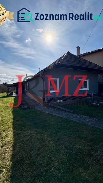 Rodinný dům v Mýtných Ludanech, obklopený zahradou, s modrou oblohou a sluncem.