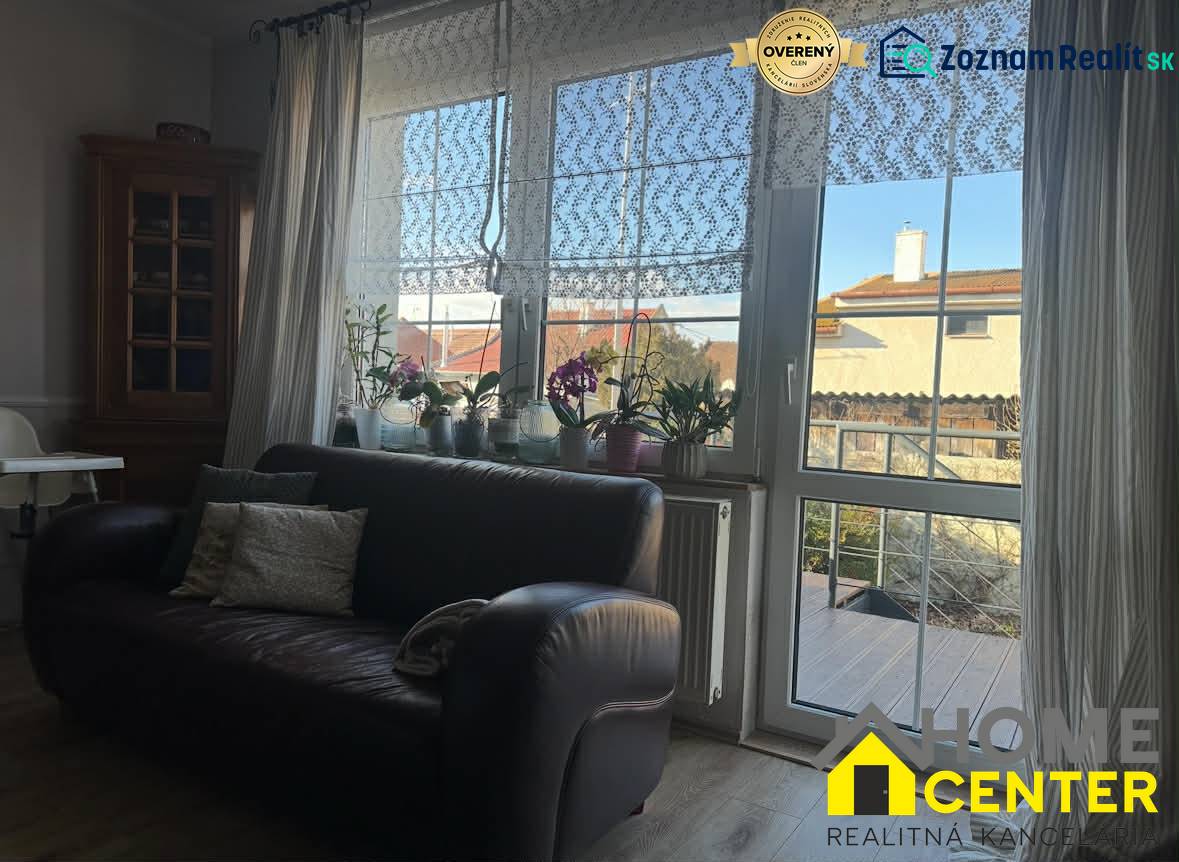 Kožená sedačka a okno s krajkovými závěsy v rodinném domě s podlahou s dřevěným dekorem.