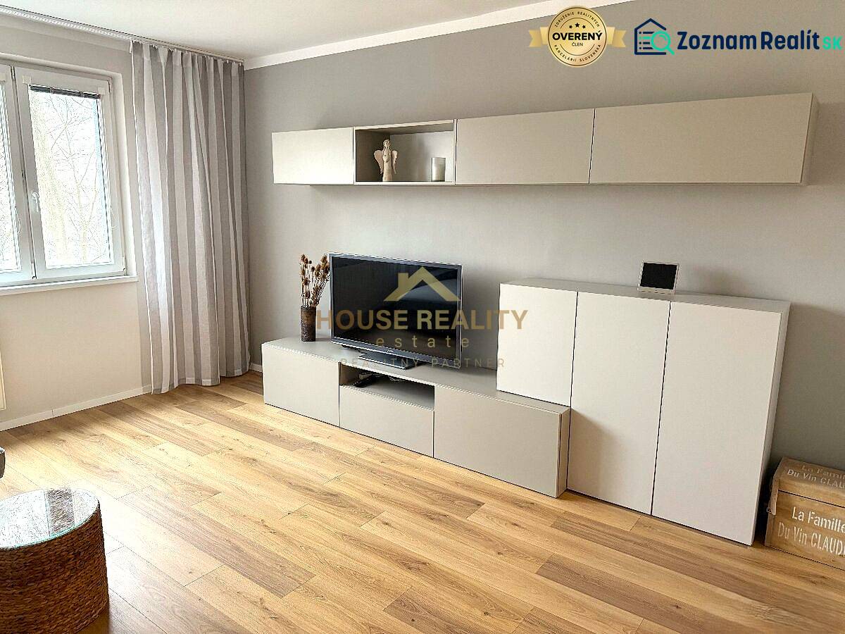 Obývací pokoj 3pokojového bytu s elegantní sestavou nábytku a podlahou s dřevěným dekorem.