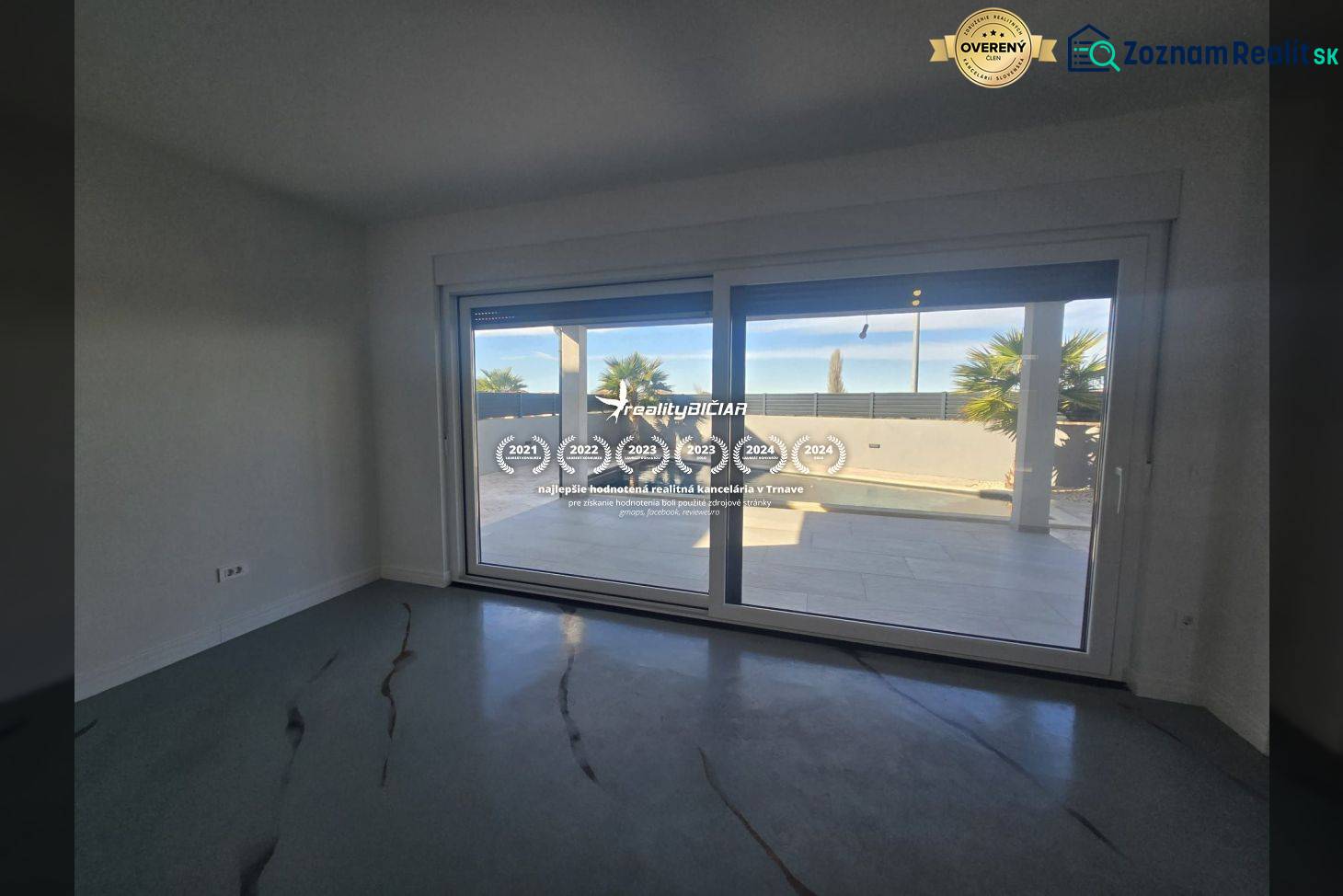 Interiér vily s velkým prosklením a výhledem na exteriér s bazénem.