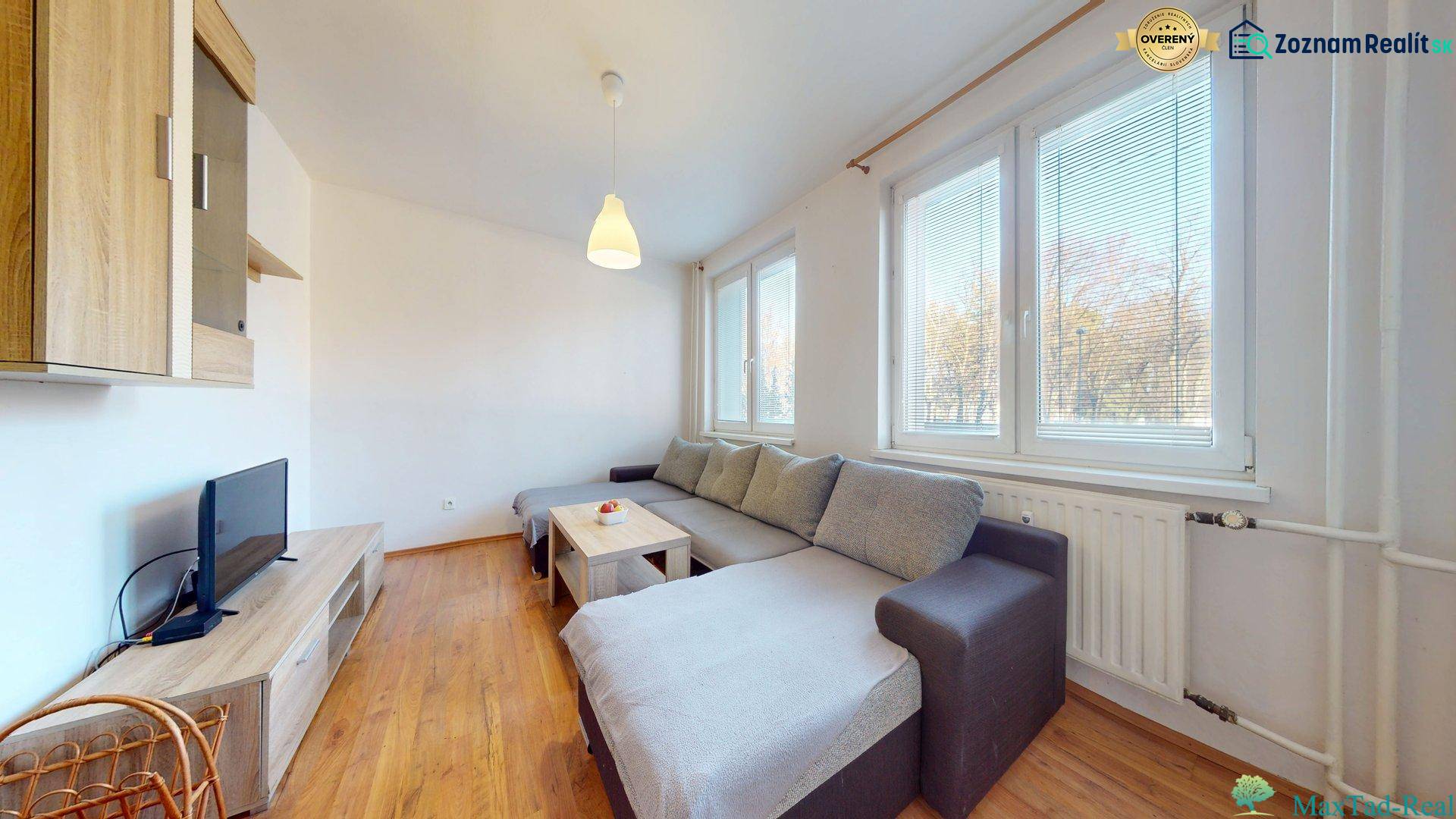 Obývací pokoj v 3pokojovém bytě s pohovkou, TV a podlahou s dřevěným dekorem.