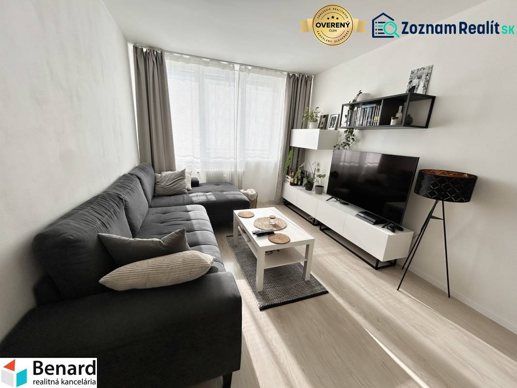 Obývací pokoj v 2-pokojovém bytě s podlahou s dřevěným dekorem a sedačkou.