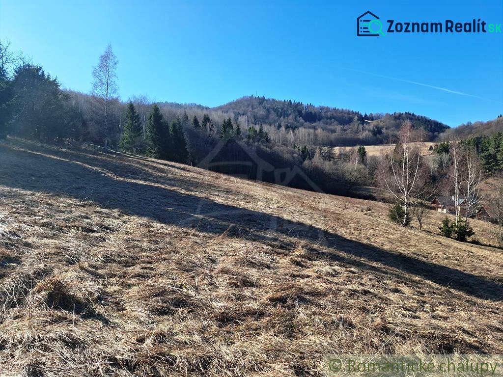 Zemědělské a lesní pozemky v Hronci s travnatými kopci a stromy v pozadí.