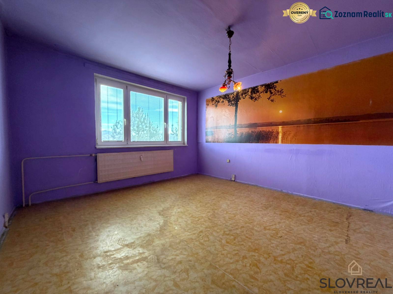 Fialově laděný pokoj v 2-pokojovém bytě s podlahou s dřevěným dekorem a velkým oknem.