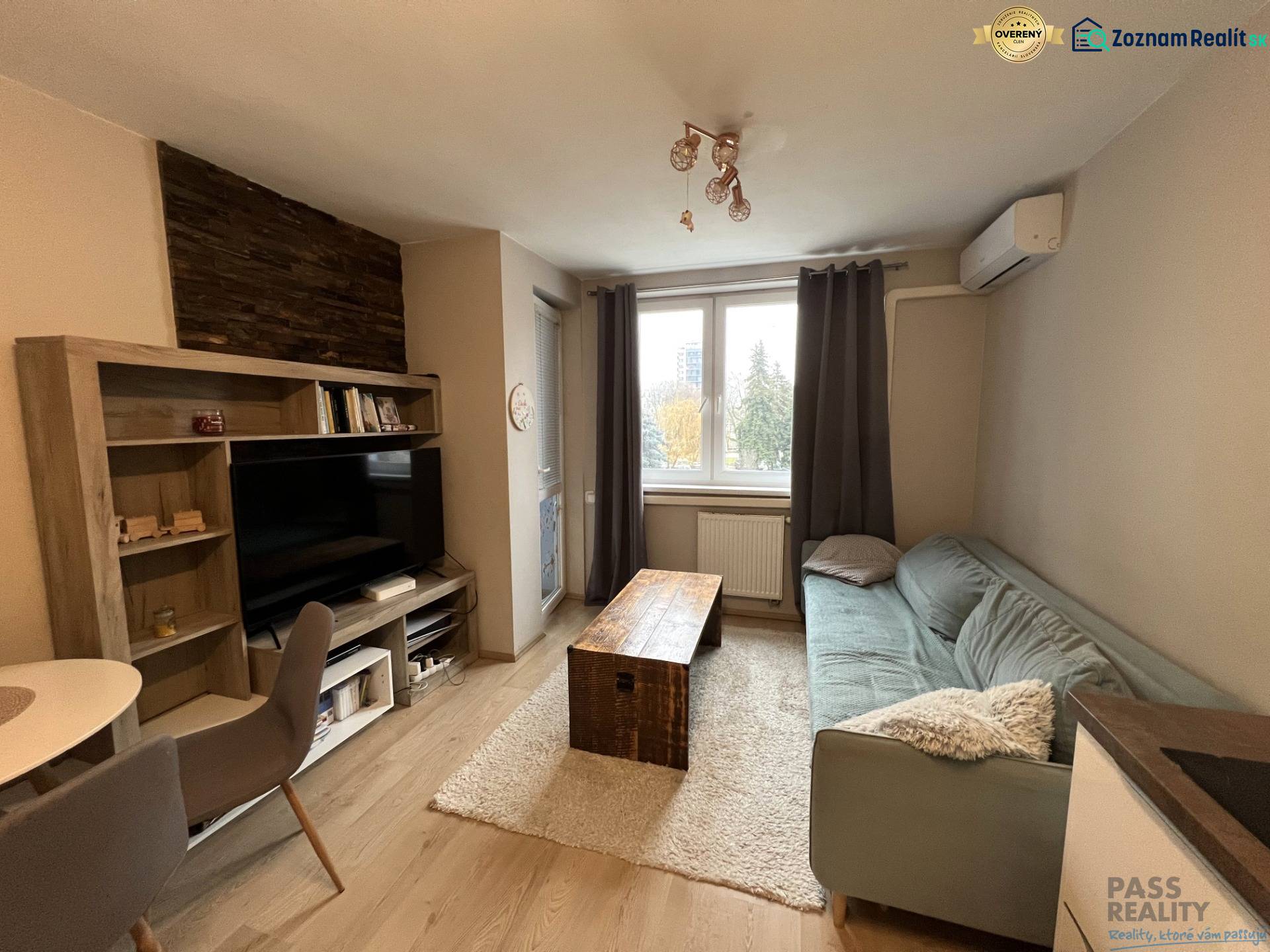 Obývací pokoj s podlahou s dřevěným dekorem, pohovkou a televizí v 2pokojovém bytě.