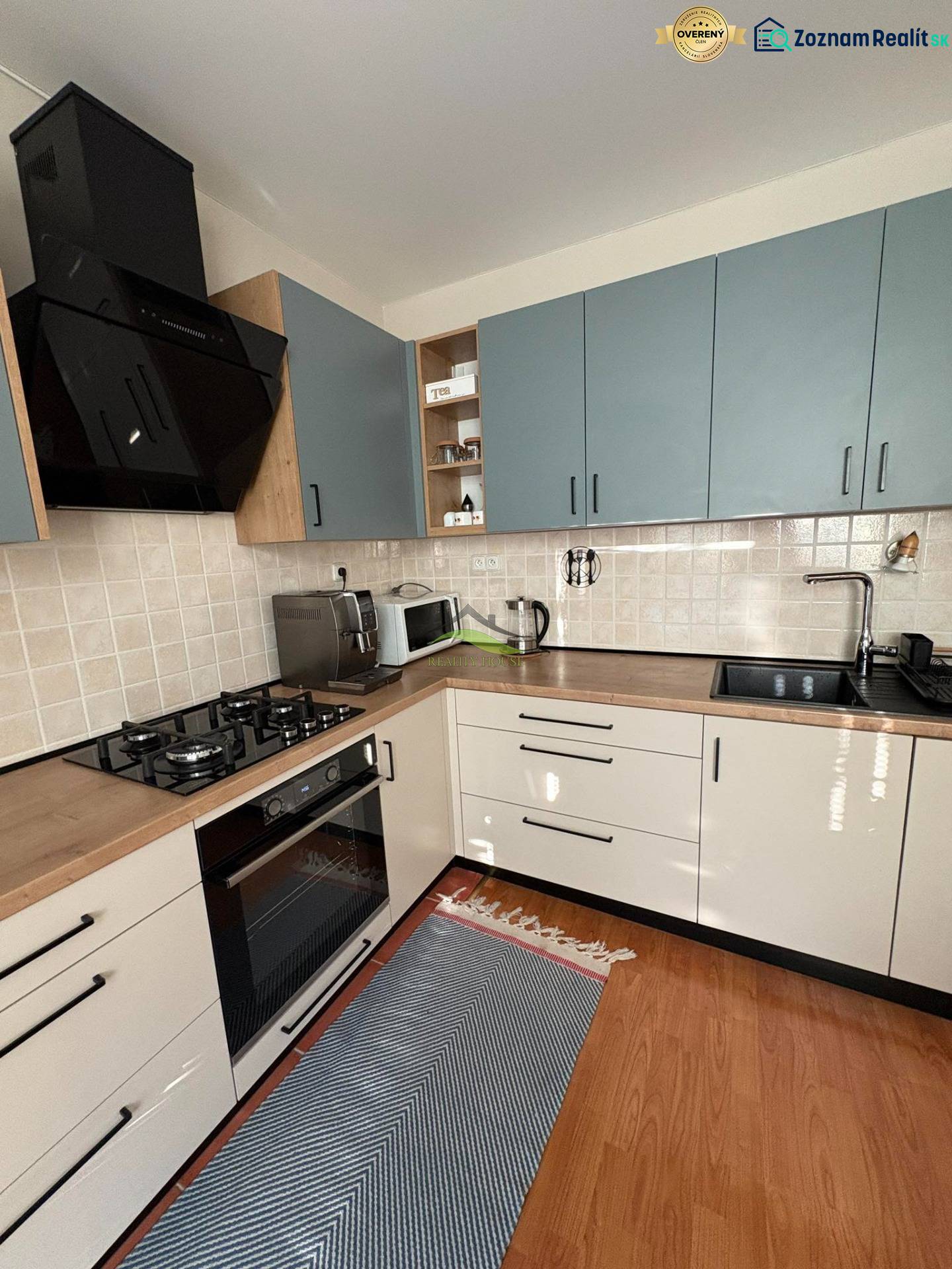 Kuchyně v 3-pokojovém bytě s kachličkovaným obkladem a podlahou s dřevěným dekorem.