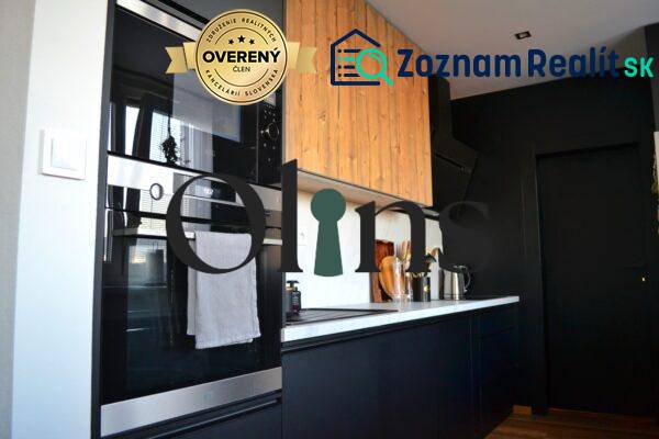 Kuchyně v 3-pokojovém bytě s černými skříňkami a vestavnou troubou, podlaha s dřevěným dekorem.