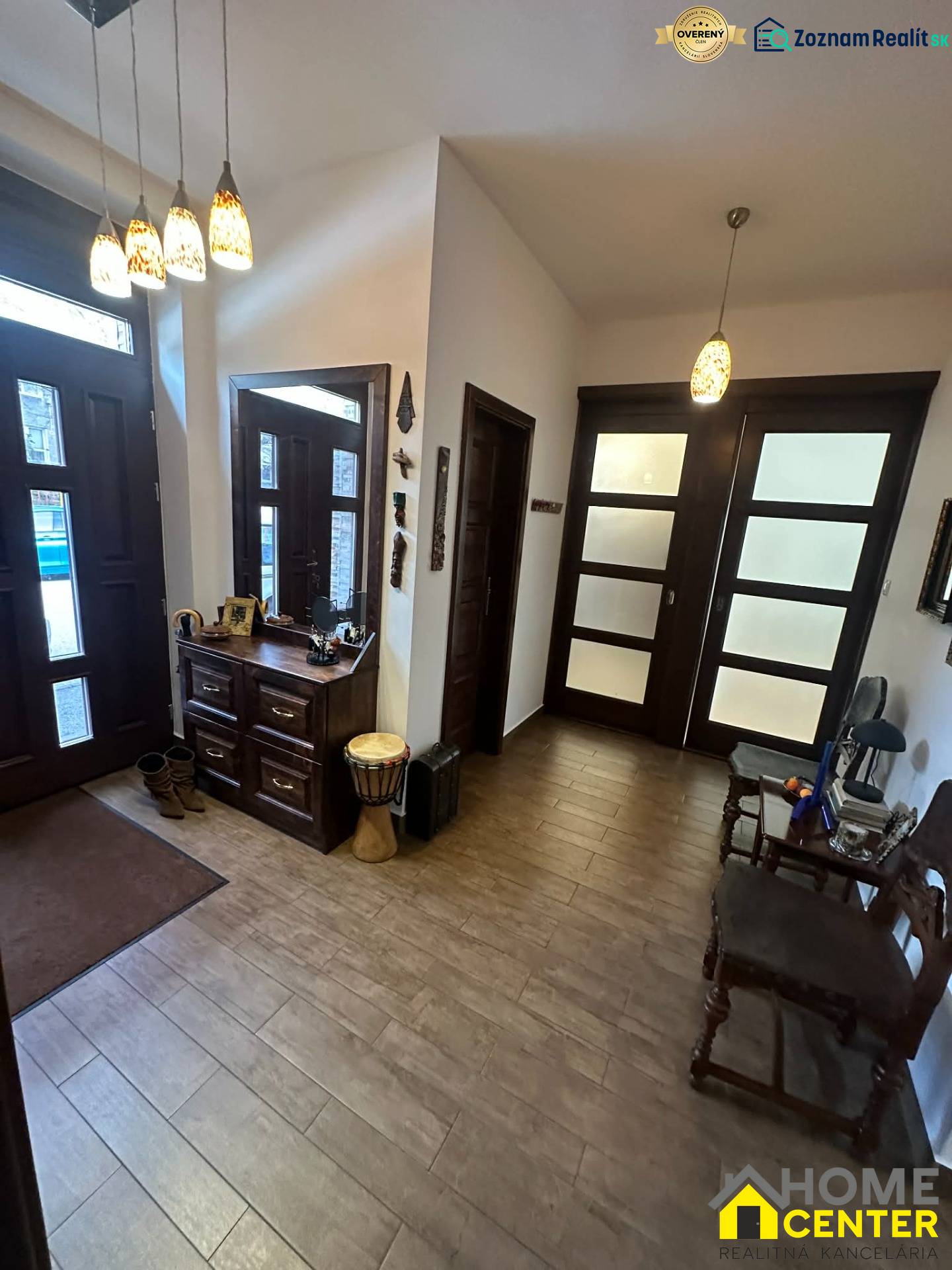 Interiér rodinného domu s podlahou s dřevěným dekorem, úložným prostorem a dekorativním osvětlením.