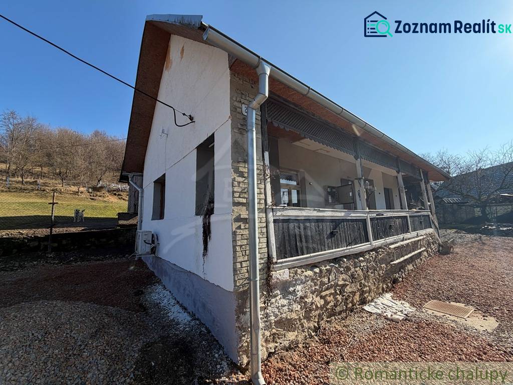 Exteriér rodinného domu v Ratkovskom Bystrom se slunečným počasím a kamennou základnou.