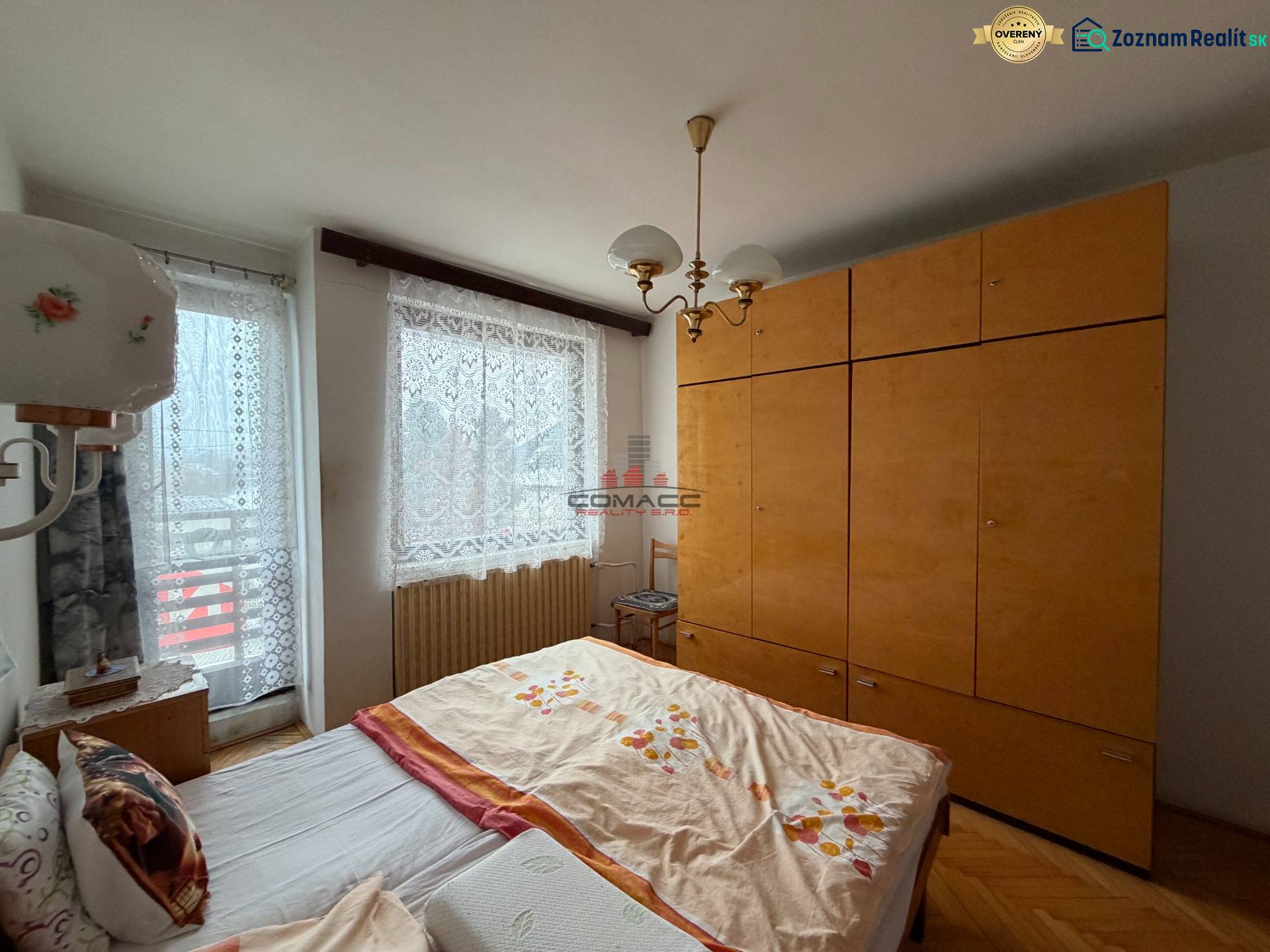 Ložnice s manželskou postelí, nábytkem a podlahou s dřevěným dekorem v rodinném domě.