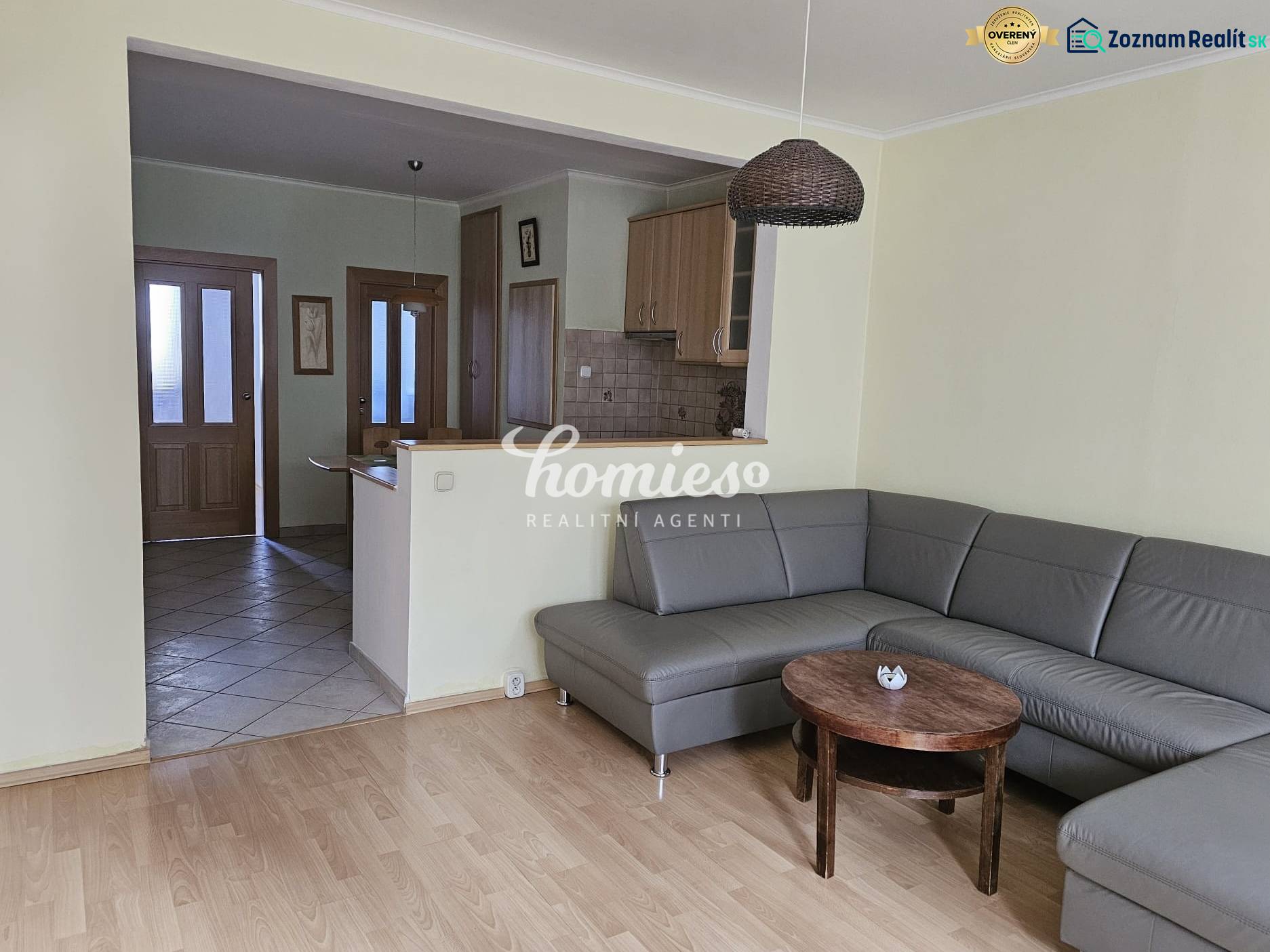 Obývací pokoj s rohovou sedačkou a podlahou s dřevěným dekorem ve 3-pokojovém bytě.