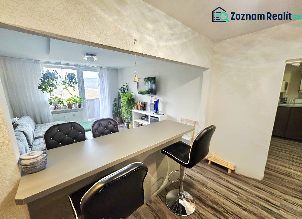 3pokojový byt s barovým pultem a pohodlným posezením, podlaha s dřevěným dekorem.