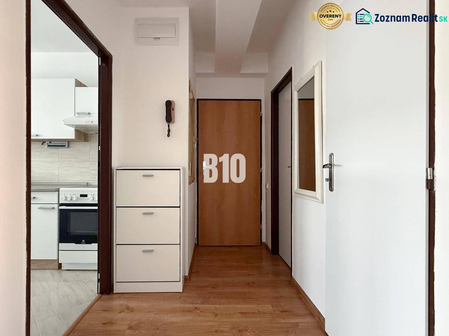 Chodba s podlahou s dřevěným dekorem v Rekreačním apartmánu, v pozadí kuchyně.