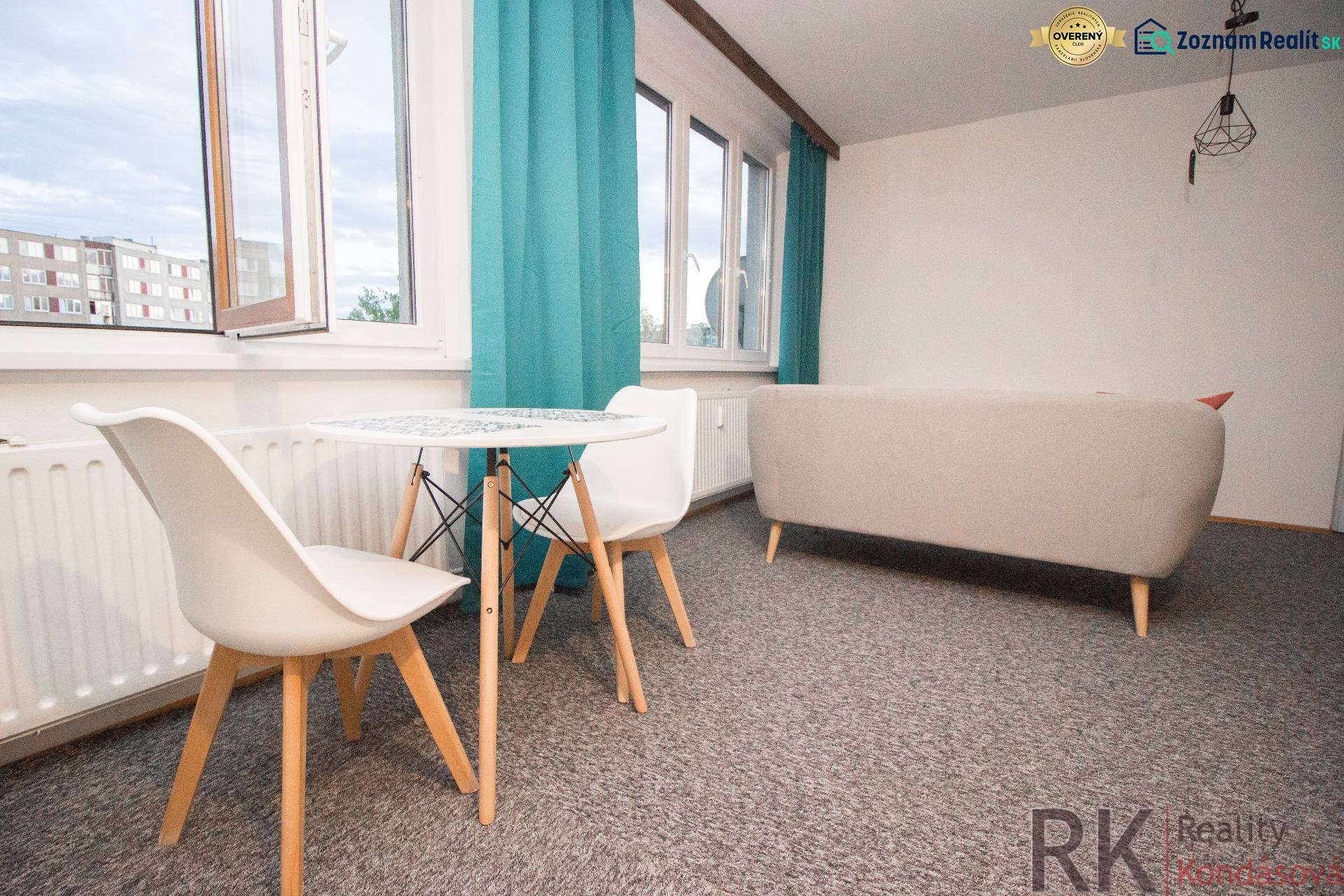Obývací pokoj se stolem a židlemi ve 4pokojovém bytě, zářivé závěsy, světlý koberec.