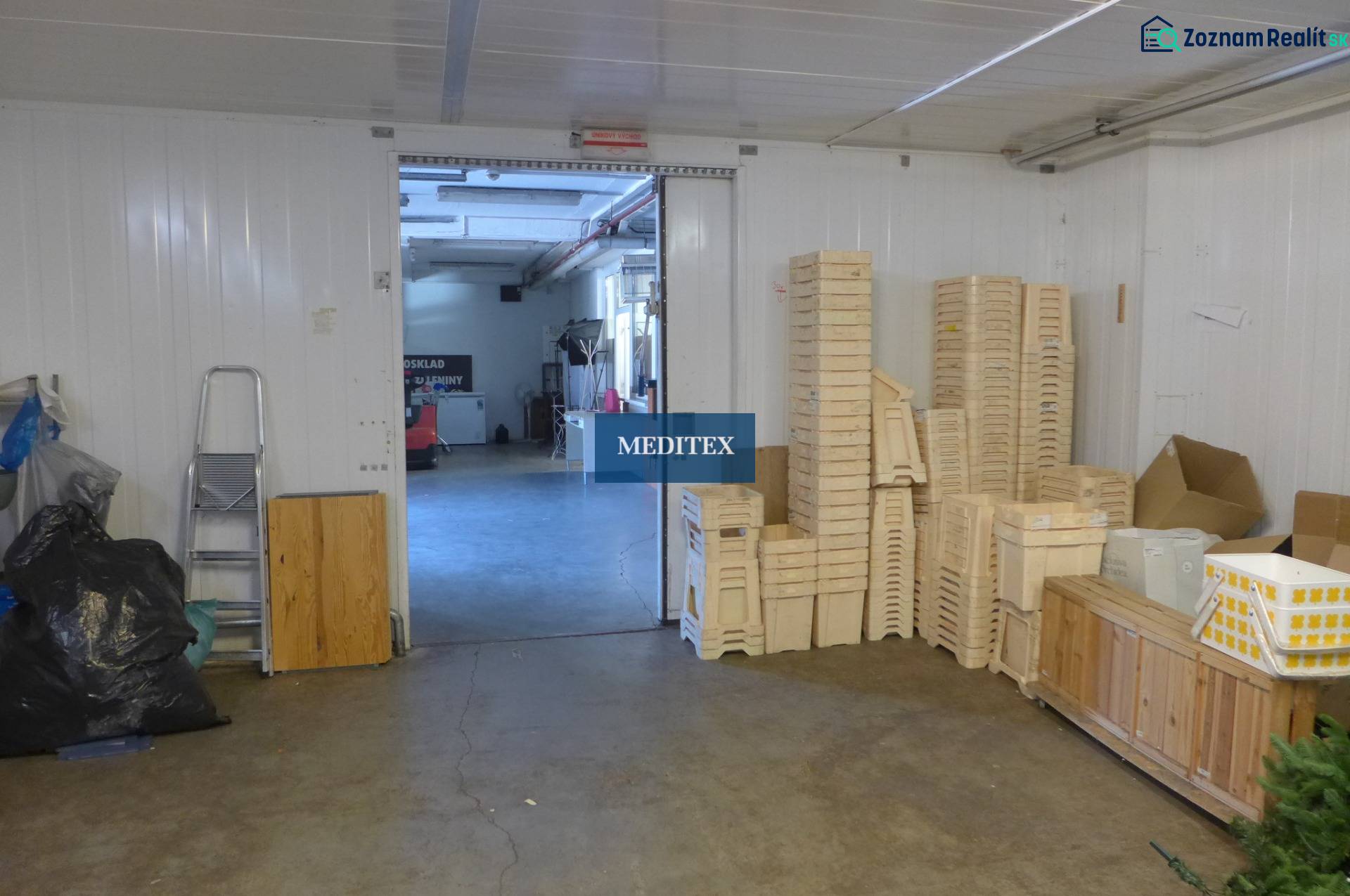 Interiér skladu s dřevěnými přepravkami a žebříkem, vhodný pro sklady a haly.