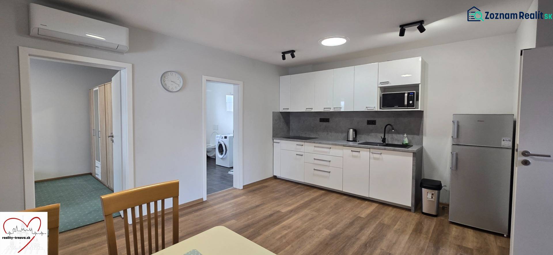 Kuchyně s bílými skříněmi a spotřebiči v 3-pokojovém bytě, podlaha s dřevěným dekorem.