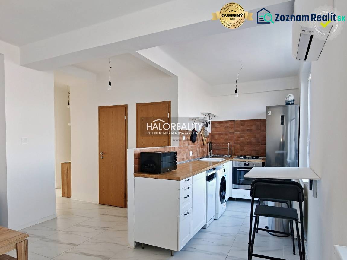 Kuchyně v 3-pokojovém bytě s bílou linkou, spotřebiči a dřevěným dekorem.