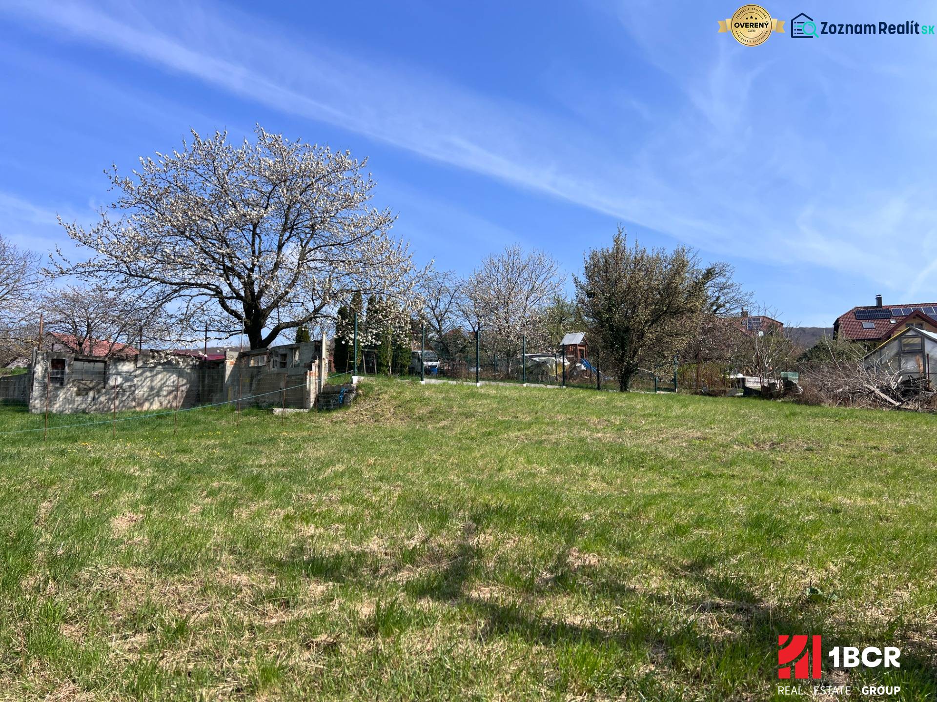 Kvetoucí stromy a travnatá plocha na pozemku pro bydlení v Mariance na Budovatelské ulici.