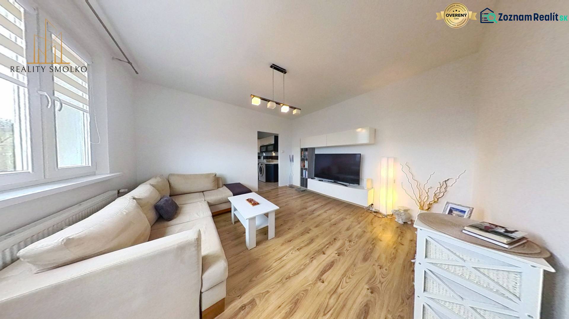 Obývací pokoj s podlahou s dřevěným dekorem v 3-pokojovém bytě se světlou sedačkou a TV skříňkou.