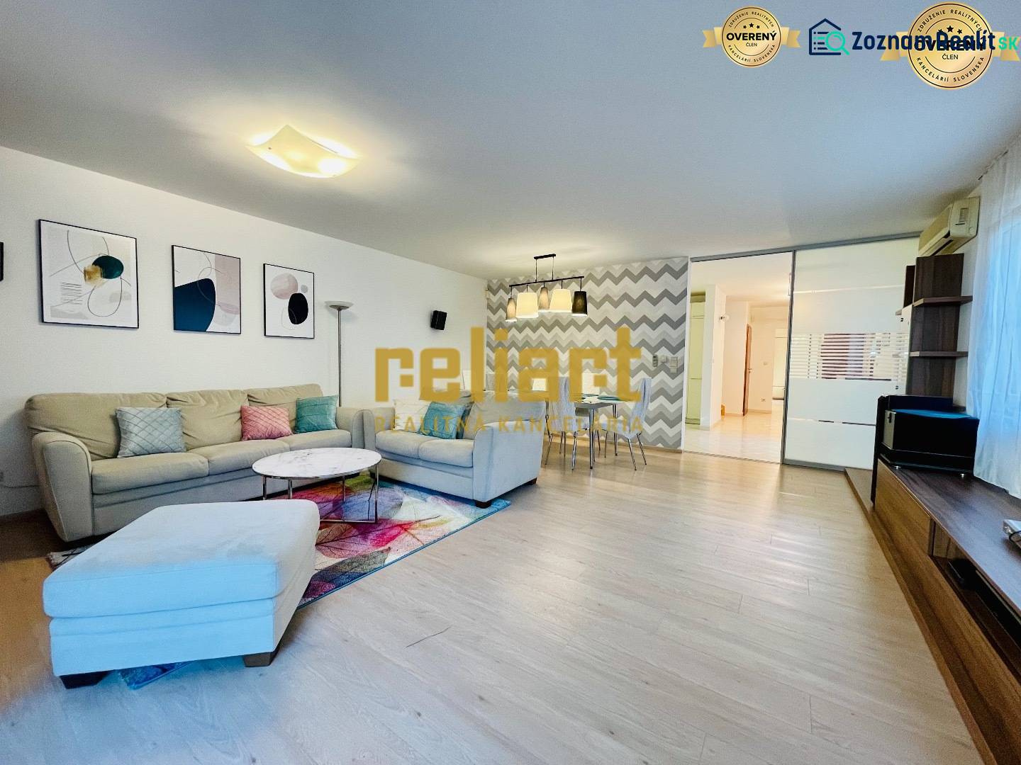 Obývací pokoj v rodinném domě s pohovkou, dekoracemi a podlahou s dřevěným dekorem.