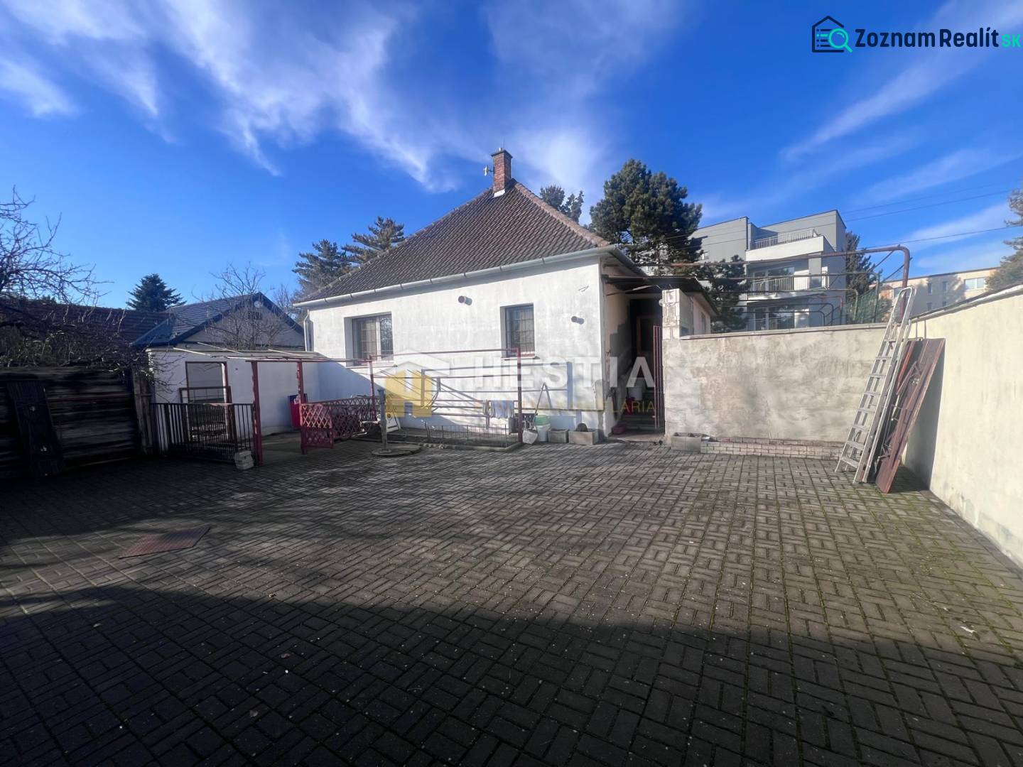 Dvorní exteriér s betonovou dlažbou a rodinným domem ve městě Senica, představený jako gastro prostory.