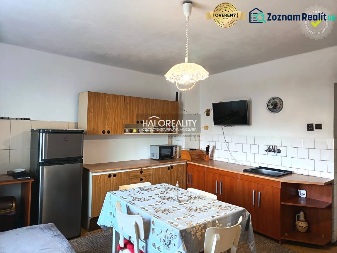 Kuchyně v rodinném domě s dřevěným kuchyňským zařízením a jídelním stolem.