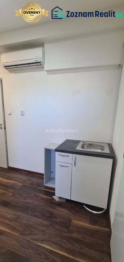 Kancelář s klimatizací, umyvadlem a podlahou s dřevěným dekorem.