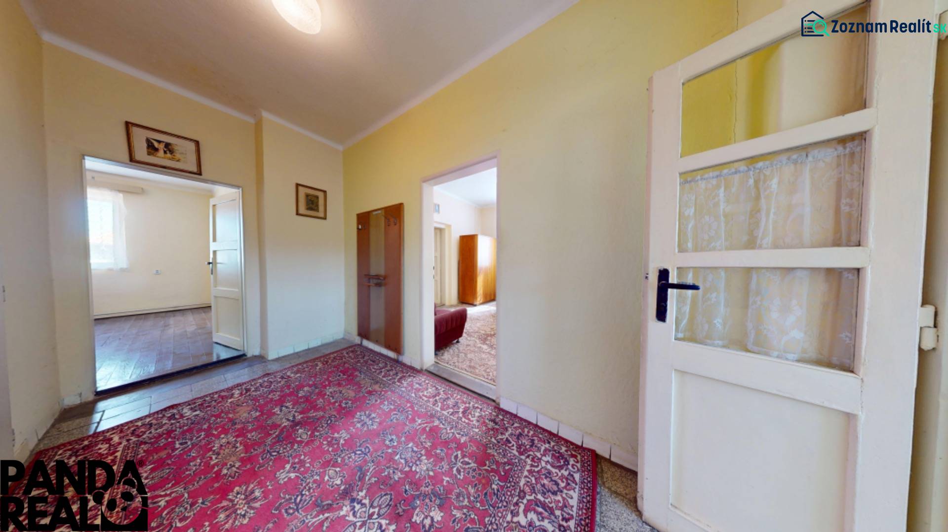 Chodba rodinného domu s kobercem a prosvětlenými místnostmi.