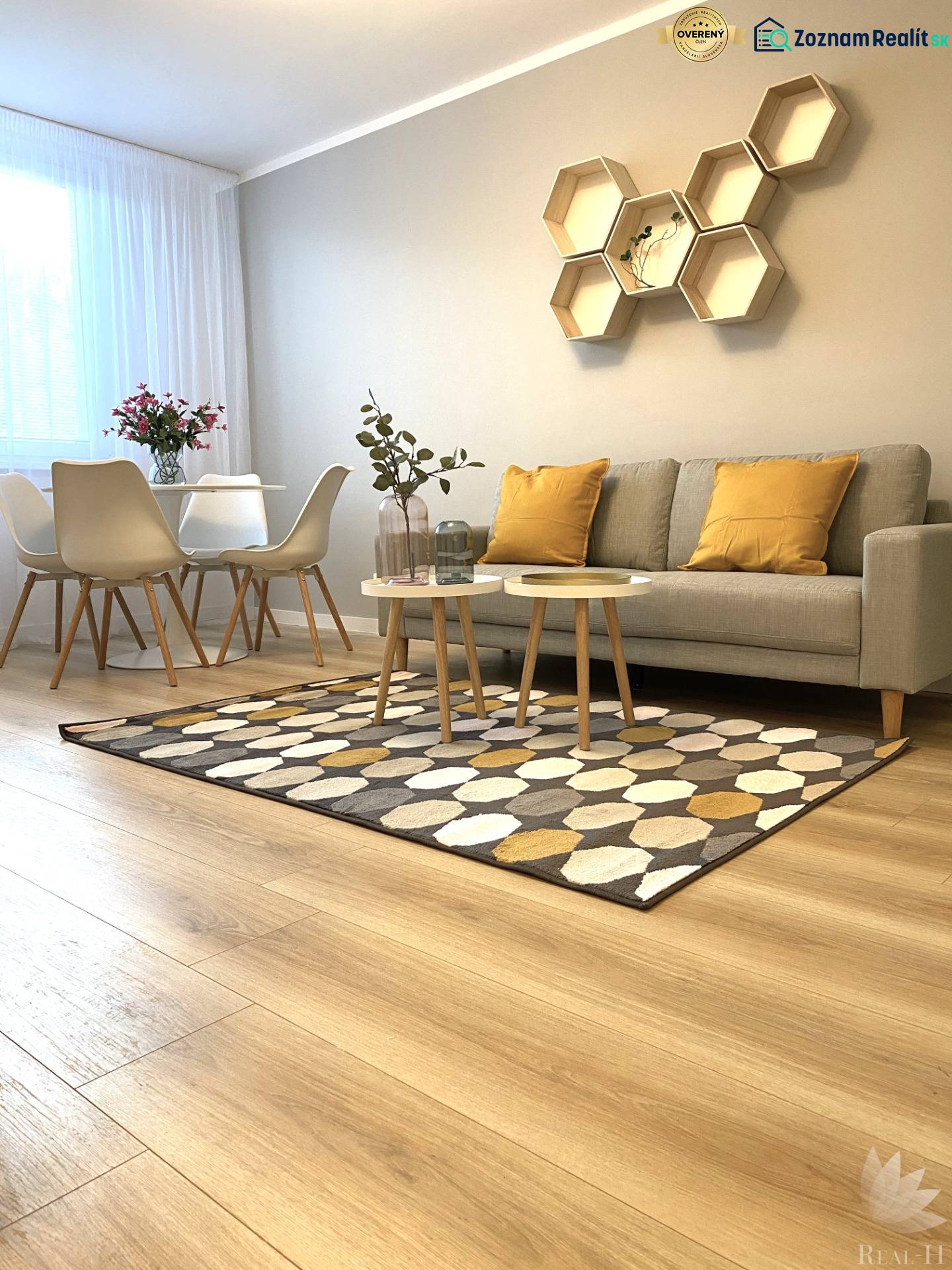 2pokojový byt s podlahou s dřevěným dekorem, pohovkou, jídelním stolem a geometrickými poličkami.