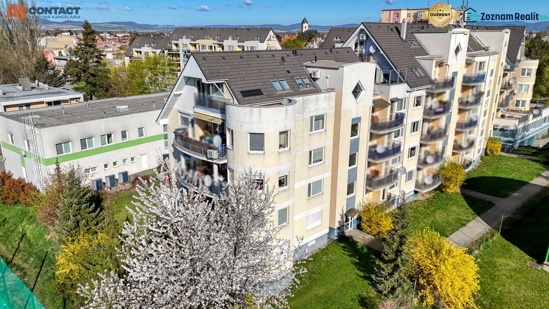 Bytový dům na ulici E. Belluša v Piešťanech, obklopený zelení.
