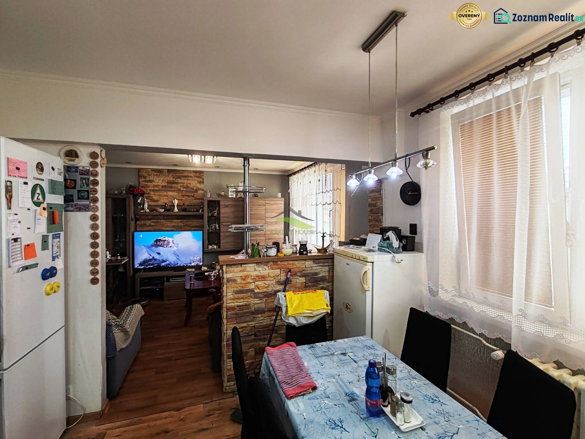 Jídelna ve 4-pokojovém bytě s podlahou s dřevěným dekorem a televizí.