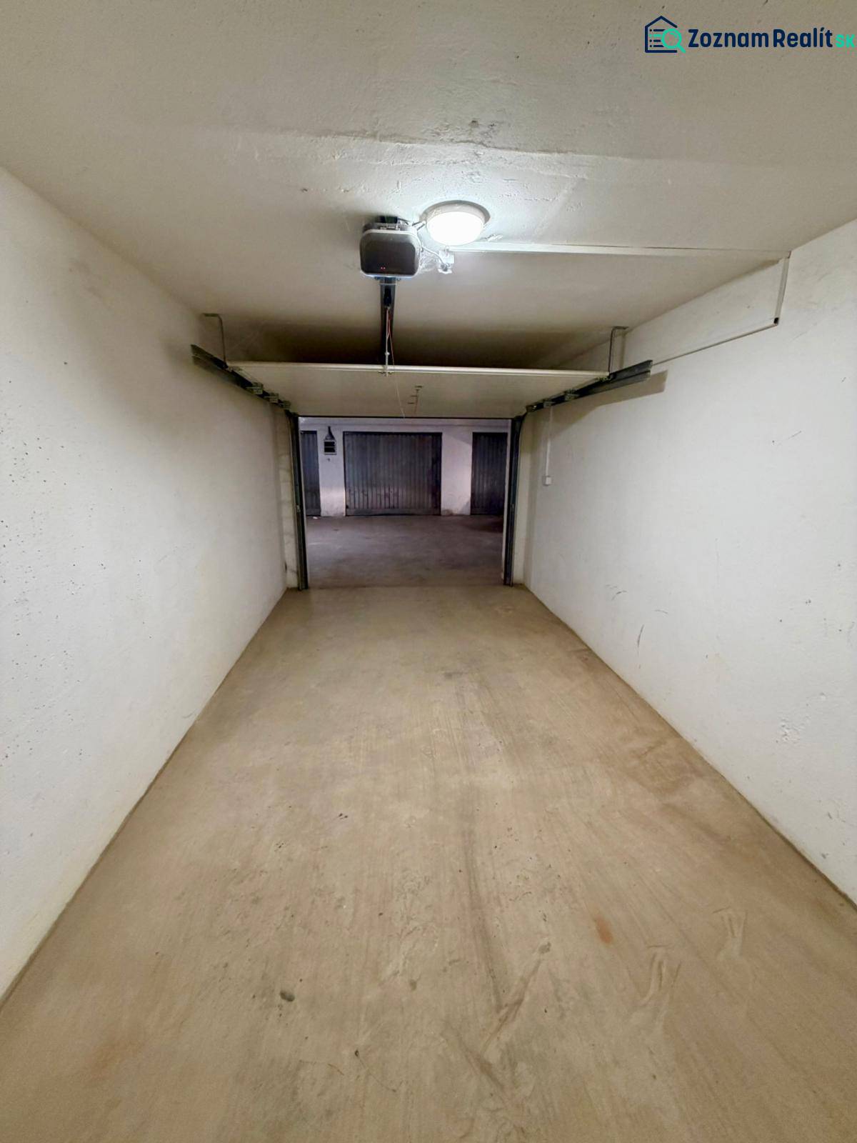 Uzavřený prostor garáže s betonovou podlahou a osvětlením.