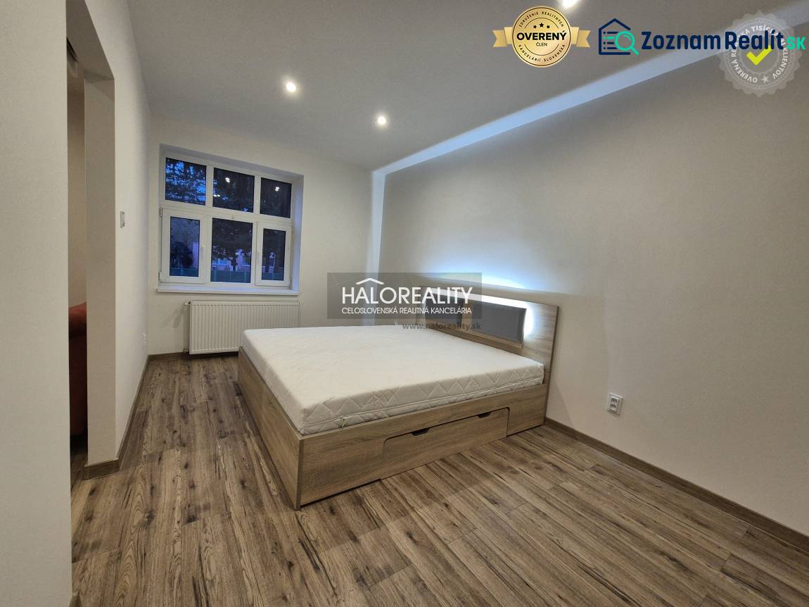 Ložnice v 2pokojovém bytě s postelí a podlahou s dřevěným dekorem.