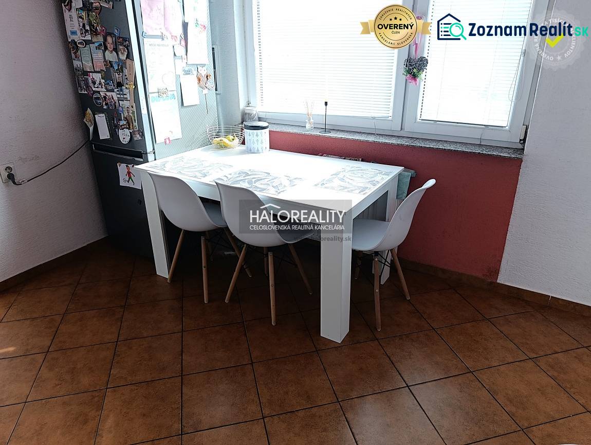 Kuchyně 2pokojového bytu s jídelním stolem, bílými židlemi a oknem.