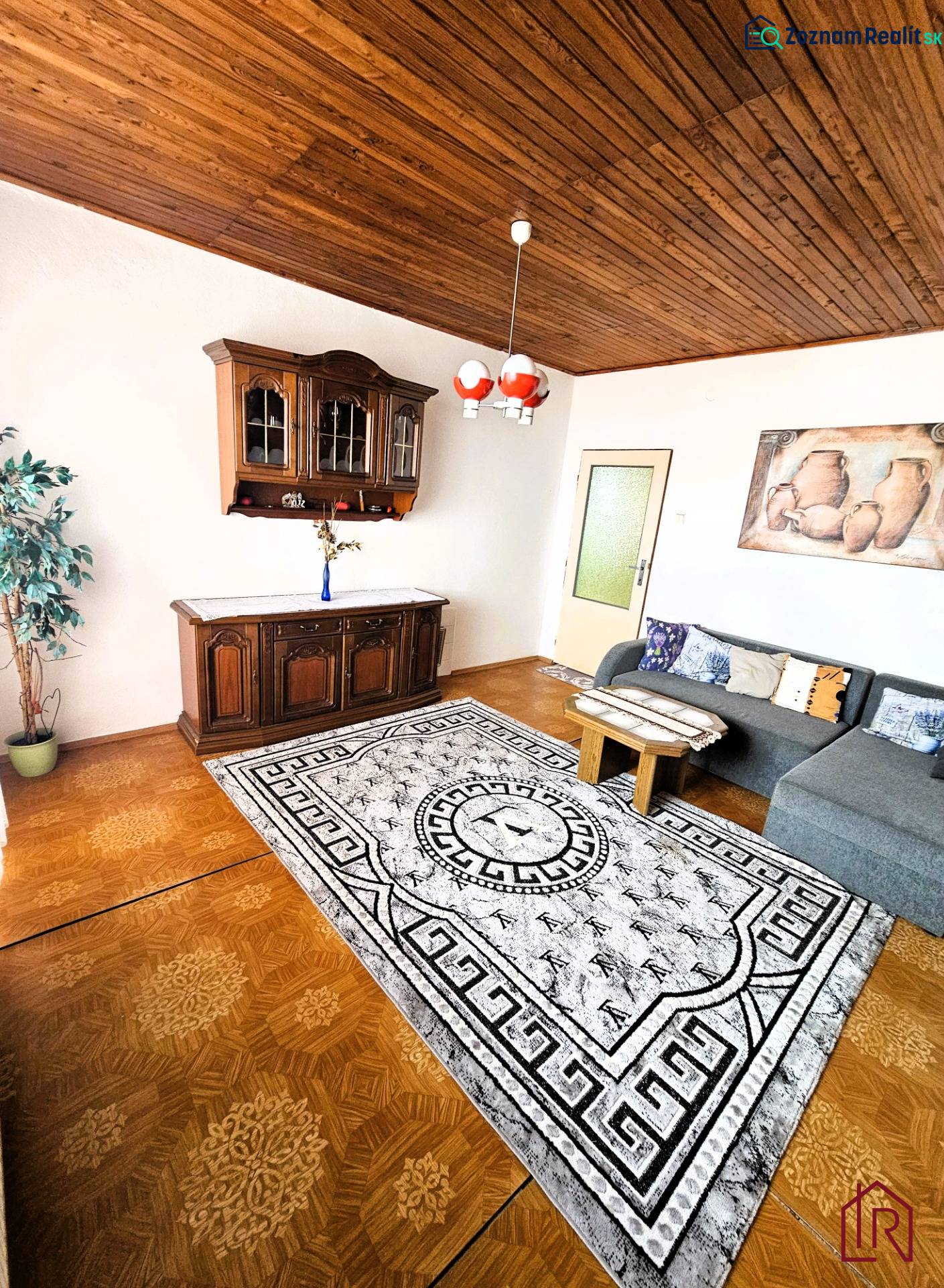 Obývací pokoj v rodinném domě s podlahou s dřevěným dekorem a sedací soupravou.