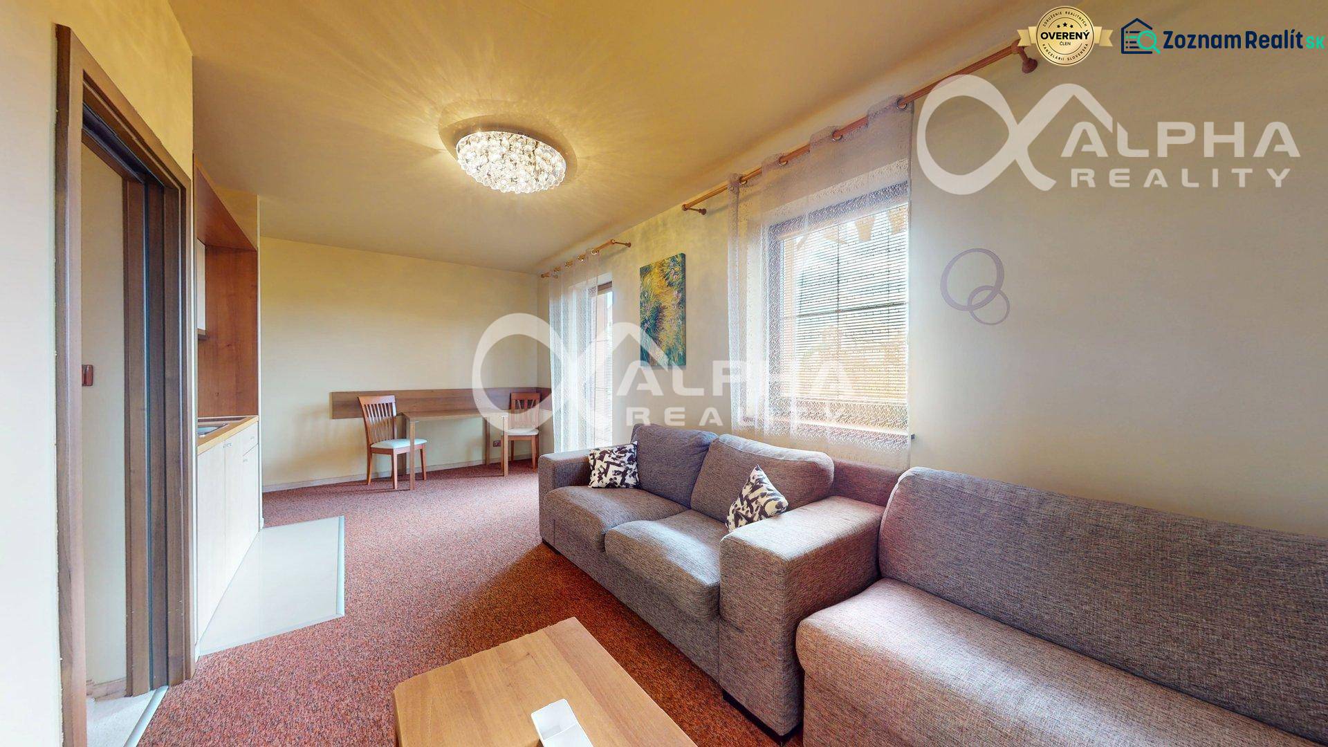 Obývací pokoj v 2pokojovém bytě s pohovkou, jídelním stolem a závěsy.