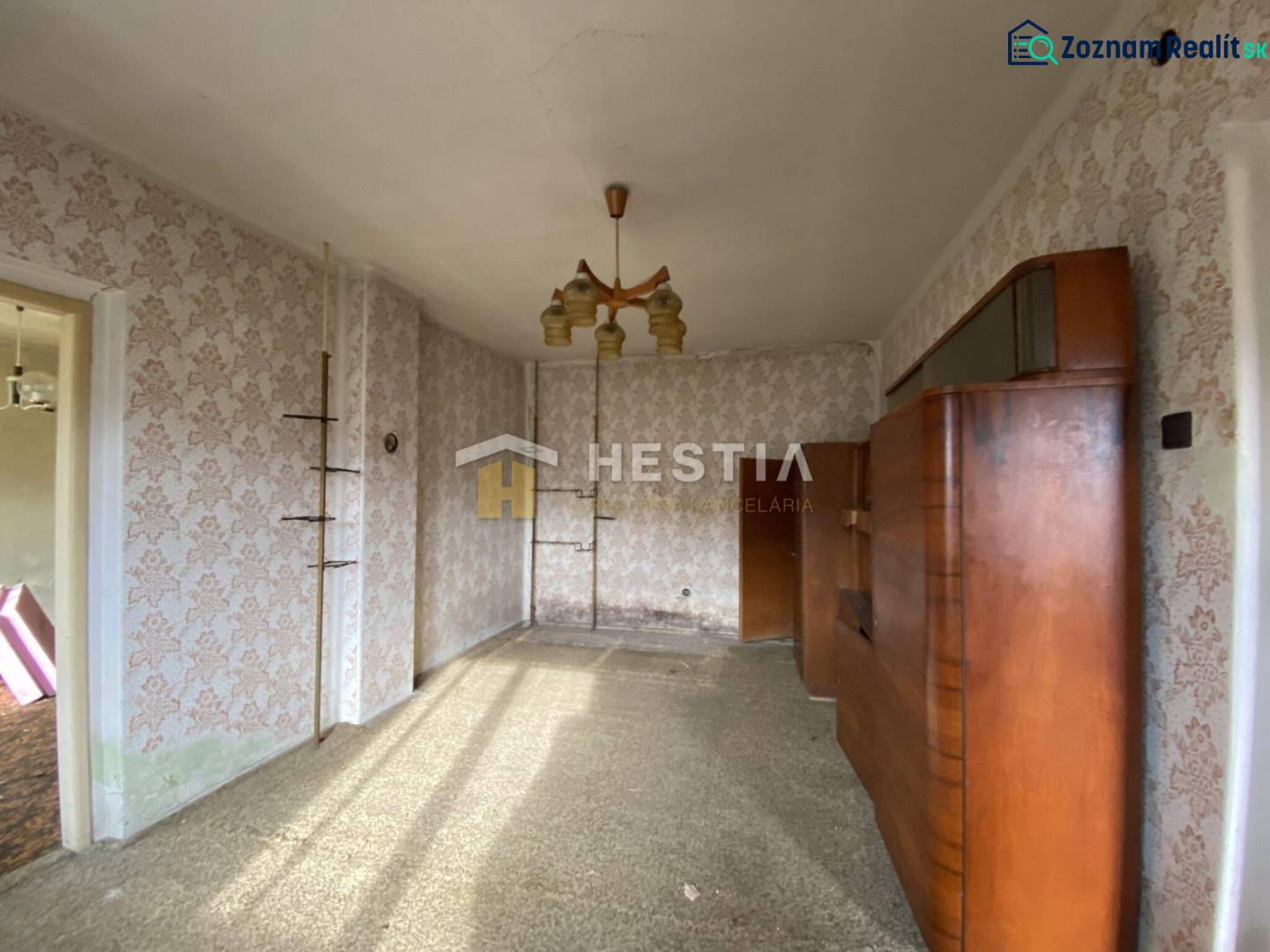 Interiér rodinného domu s retro tapetami a dřevěnou obývací stěnou.