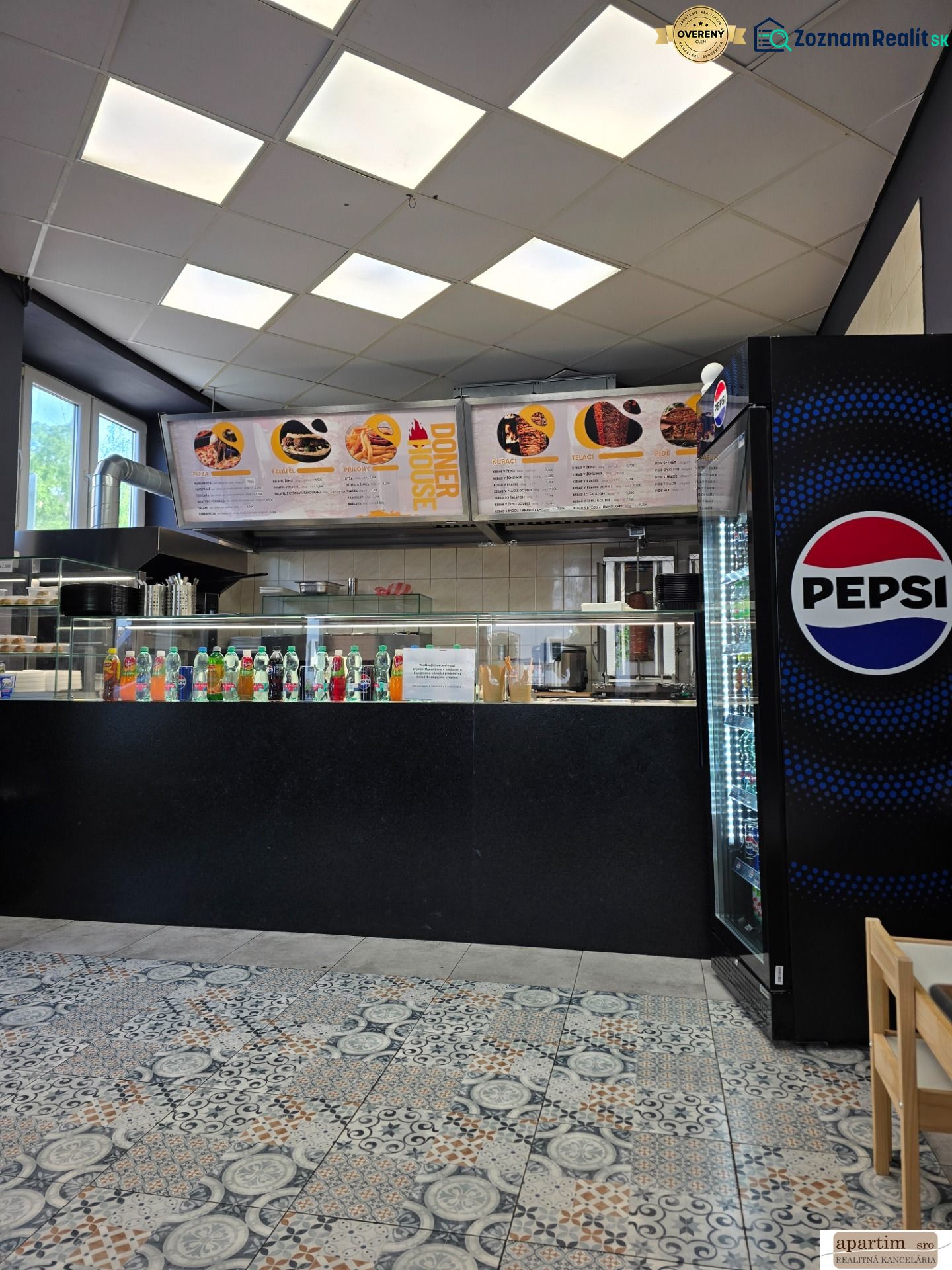 Gastro prostory s nabídkou nápojů, ledničkou Pepsi a dlažbou s ornamenty.