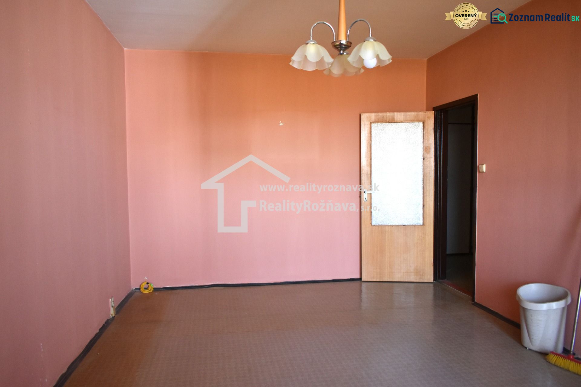 Pokoj s růžovými stěnami a hnědou podlahou ve 3-pokojovém bytě.